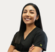 Smiling person in black scrubs with arms crossed on a plain white background