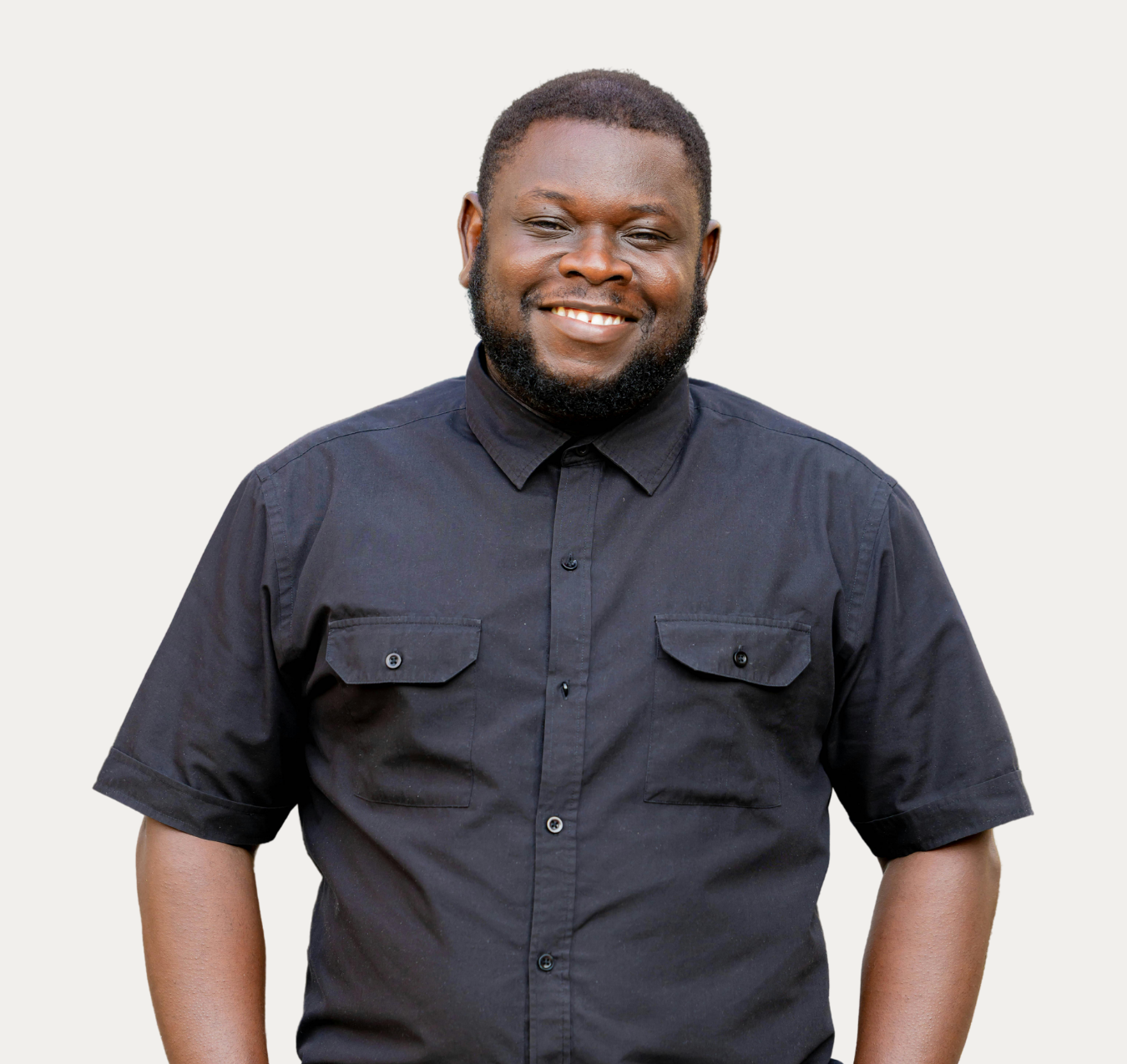 Smiling person in a black button-up shirt standing against a plain light background