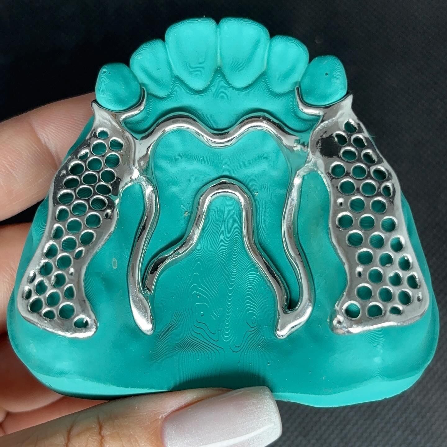 A person is holding a model of a tooth with holes in it