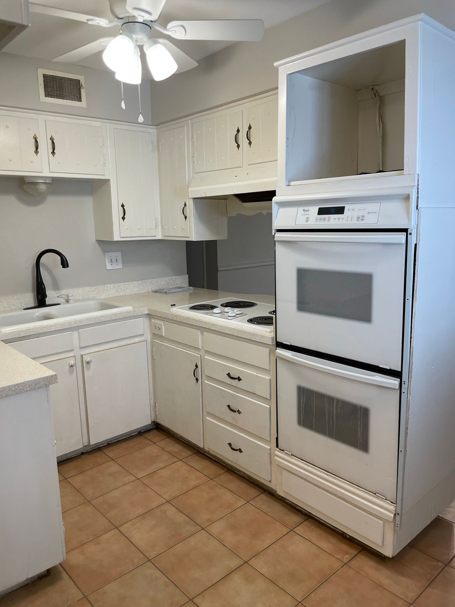 A kitchen with white cabinets and a double oven