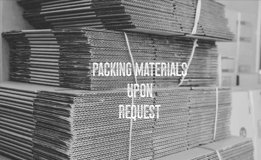 Stacked cardboard sheets with overlaid text reading “Packing materials upon request.”
