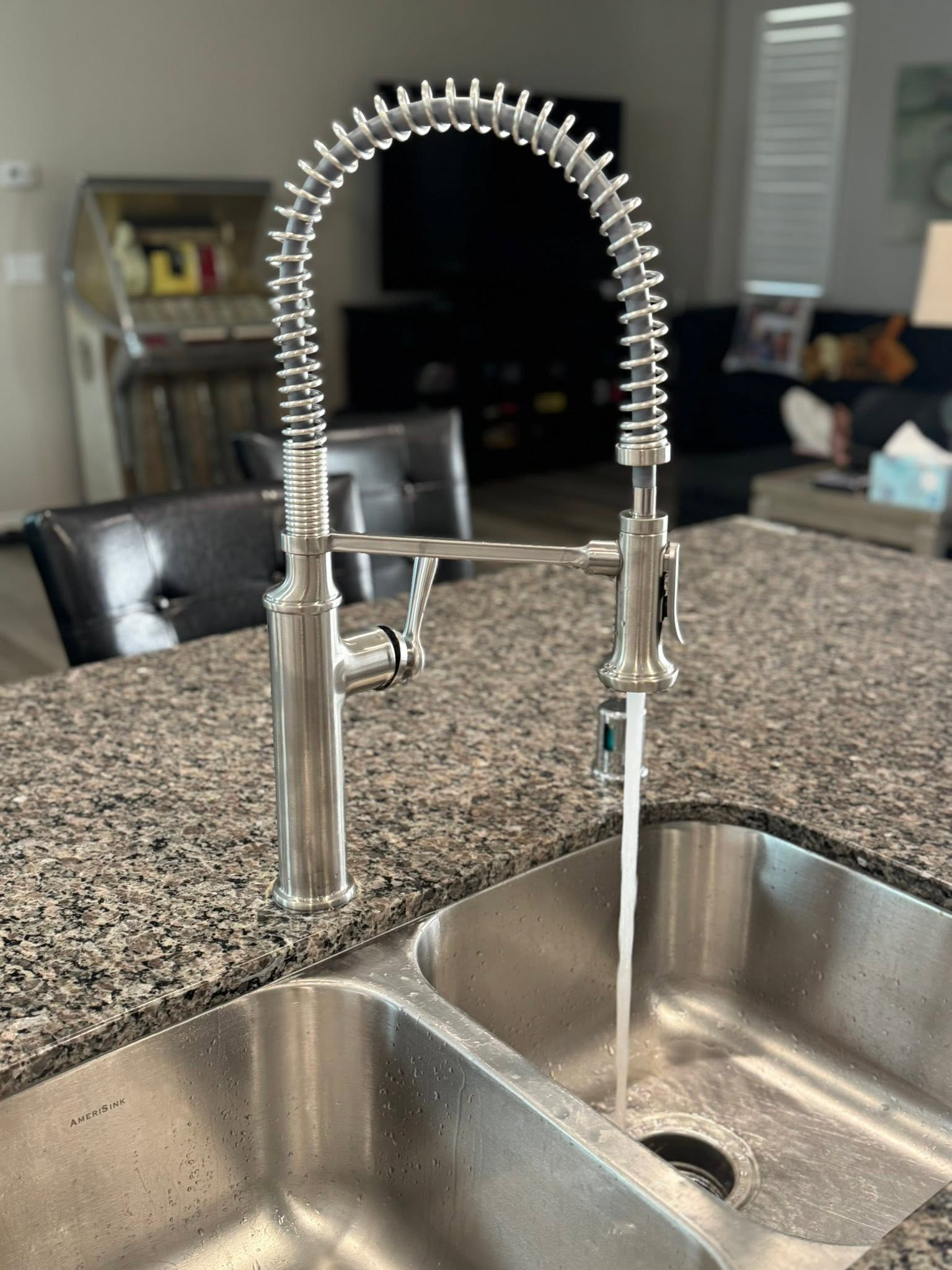 Stainless steel kitchen faucet with spring coil over a granite countertop and sink
