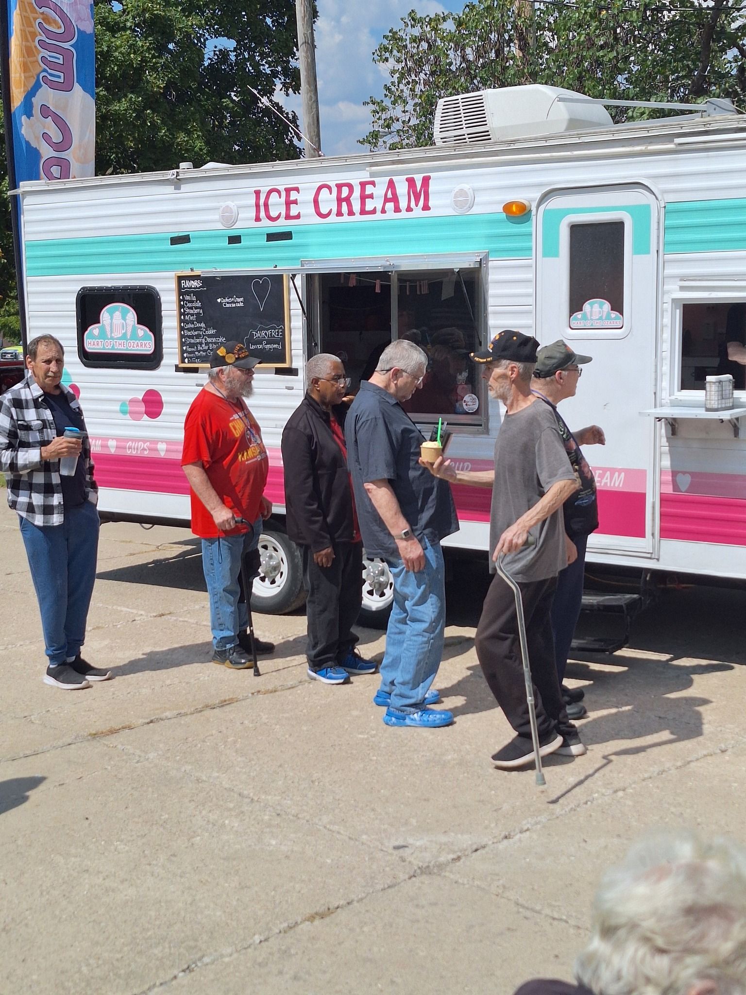 A group of people are standing in front of an ice cream truck.