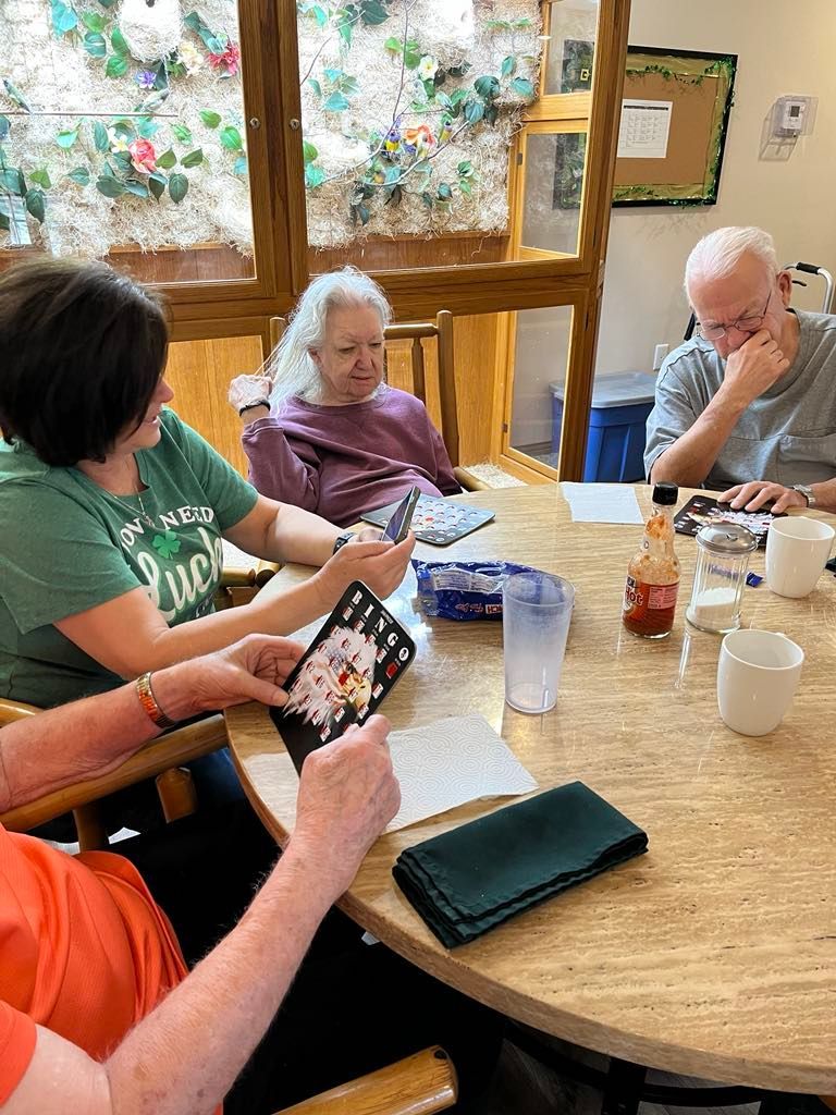 A group of elderly people are sitting around a table playing cards | Top memory care facilities near Springfield MO