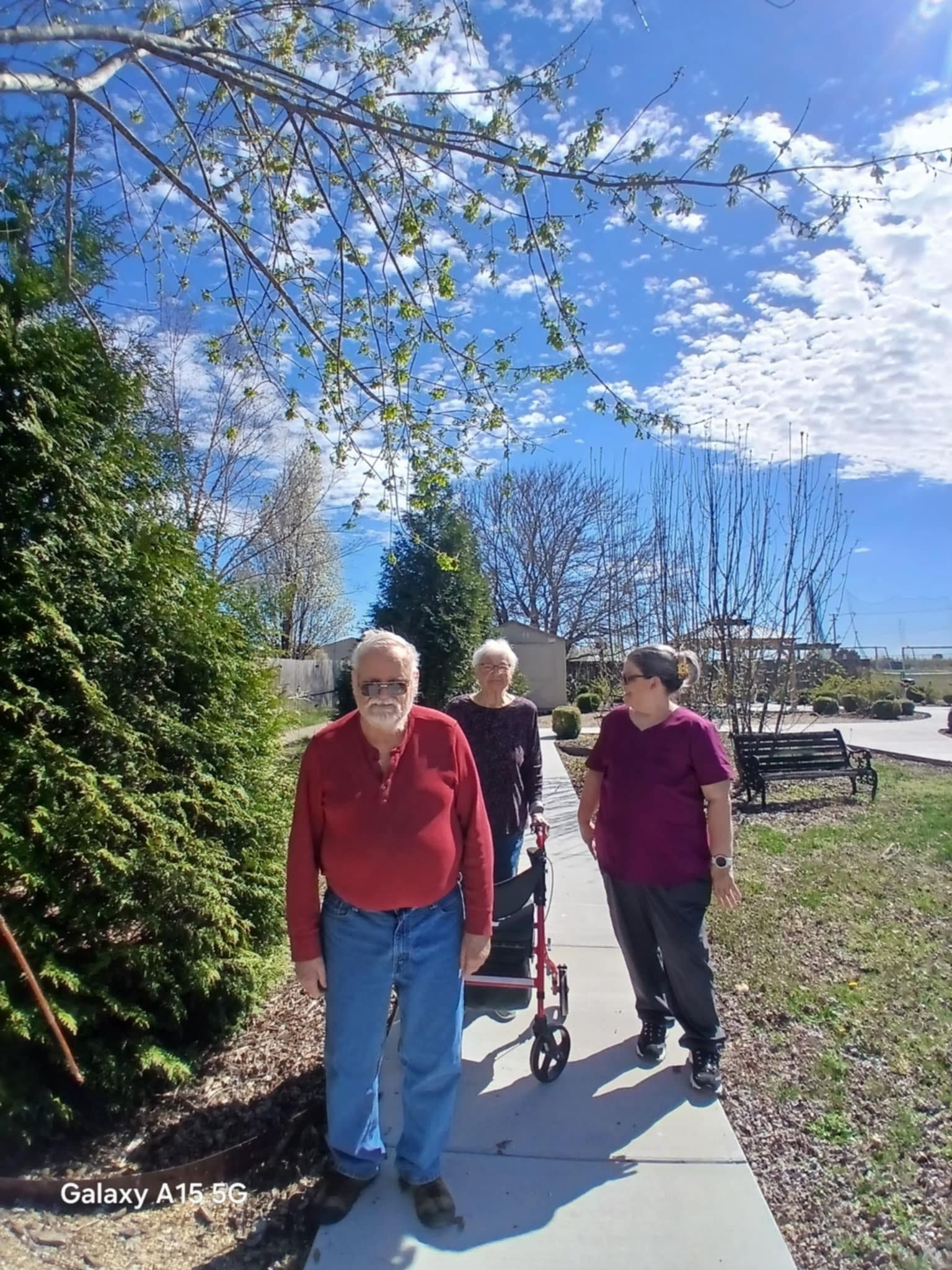 A group of people are walking down a sidewalk on a sunny day.