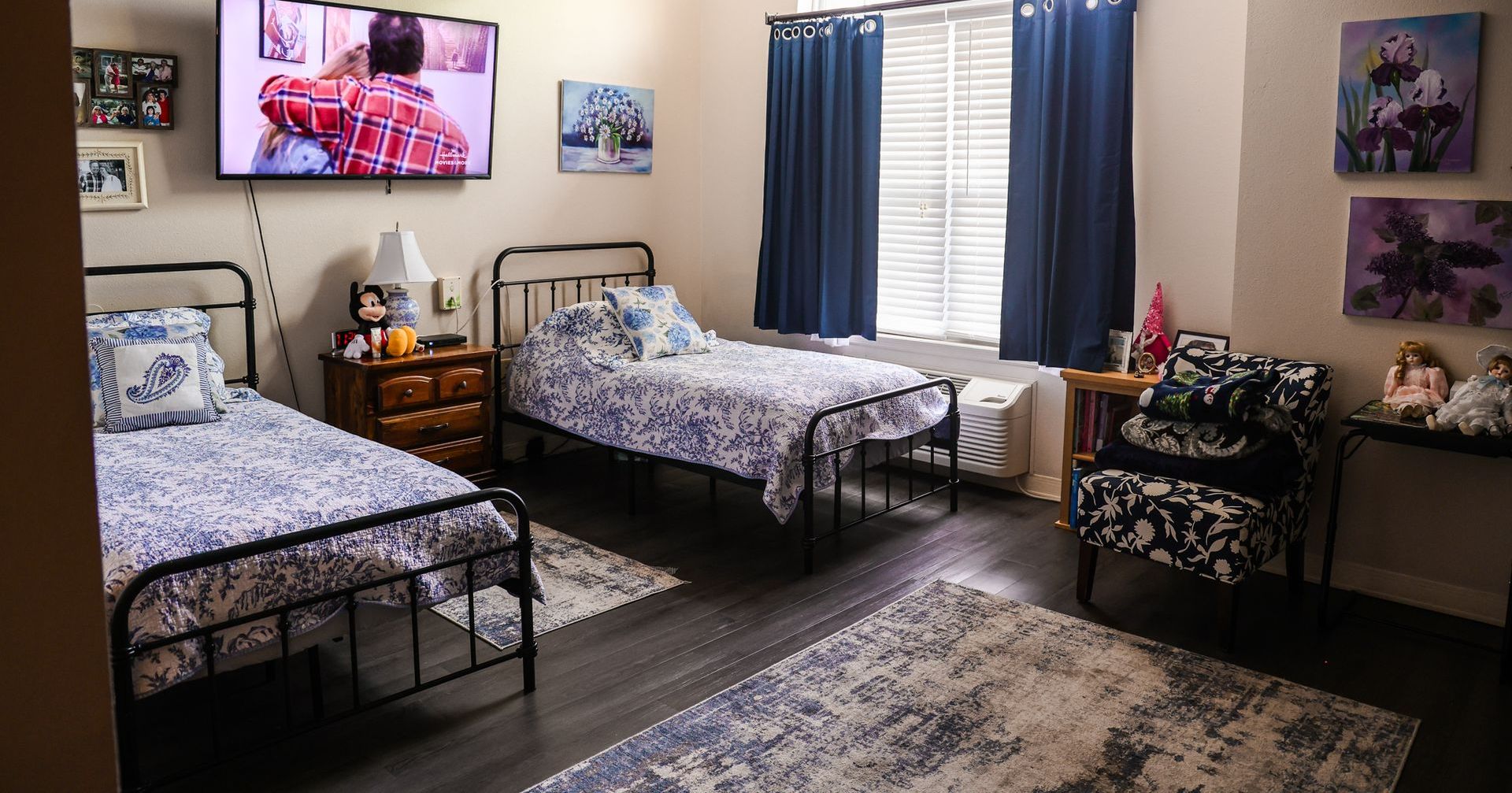 A bedroom with three beds and a television on the wall.