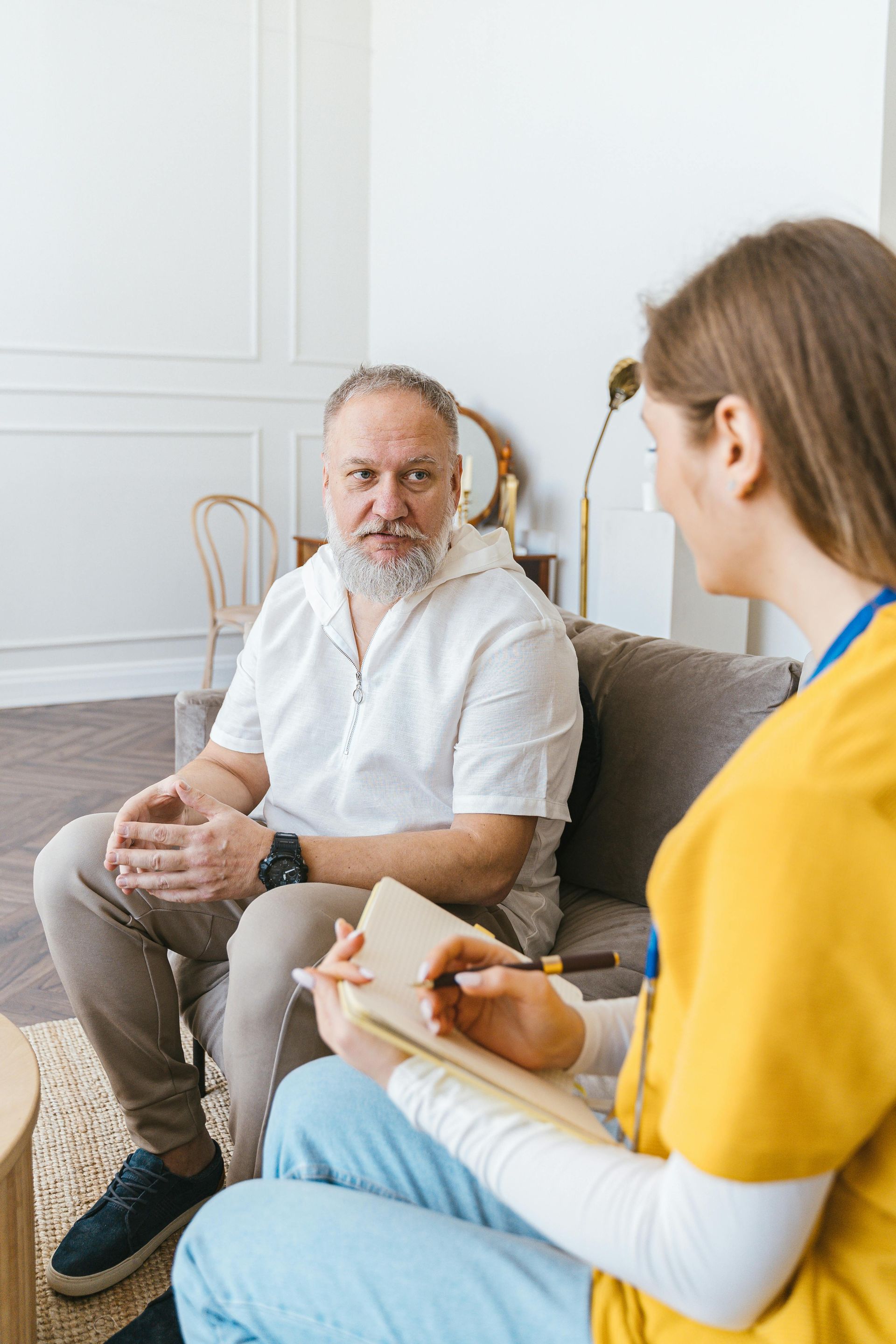 A woman is sitting on a couch talking to an older man.