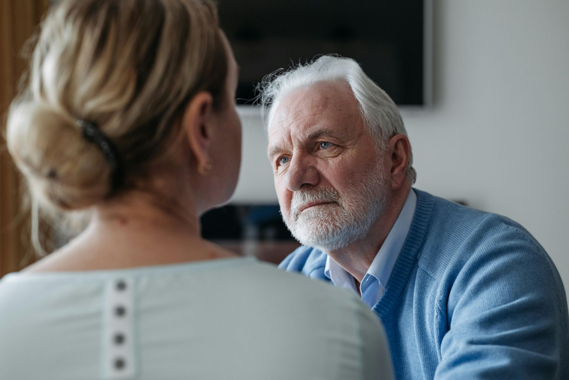 An elderly man and a young woman are talking to each other.