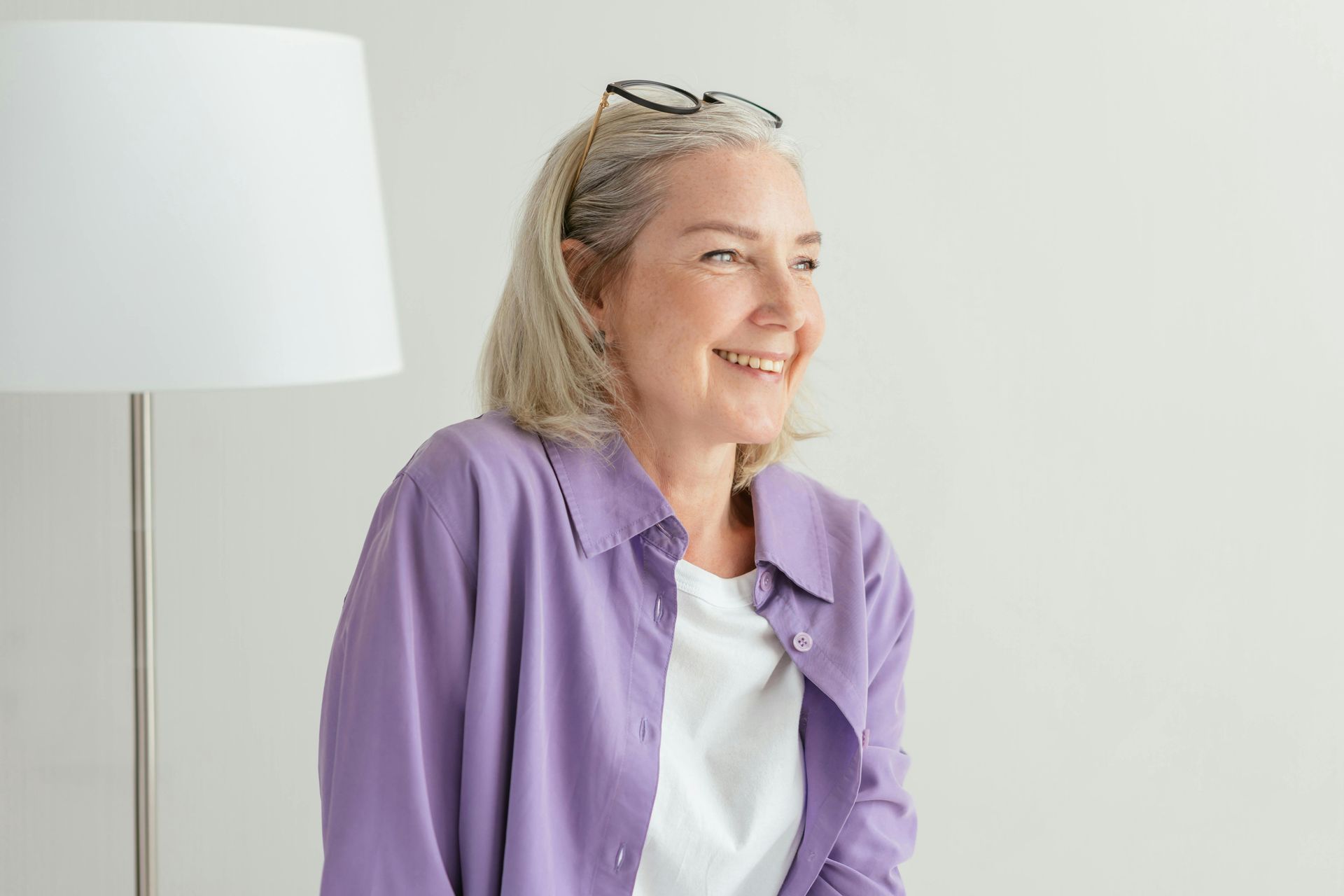 A woman in a purple shirt is smiling while sitting in front of a lamp | Best assisted living apartments in Ozark MO