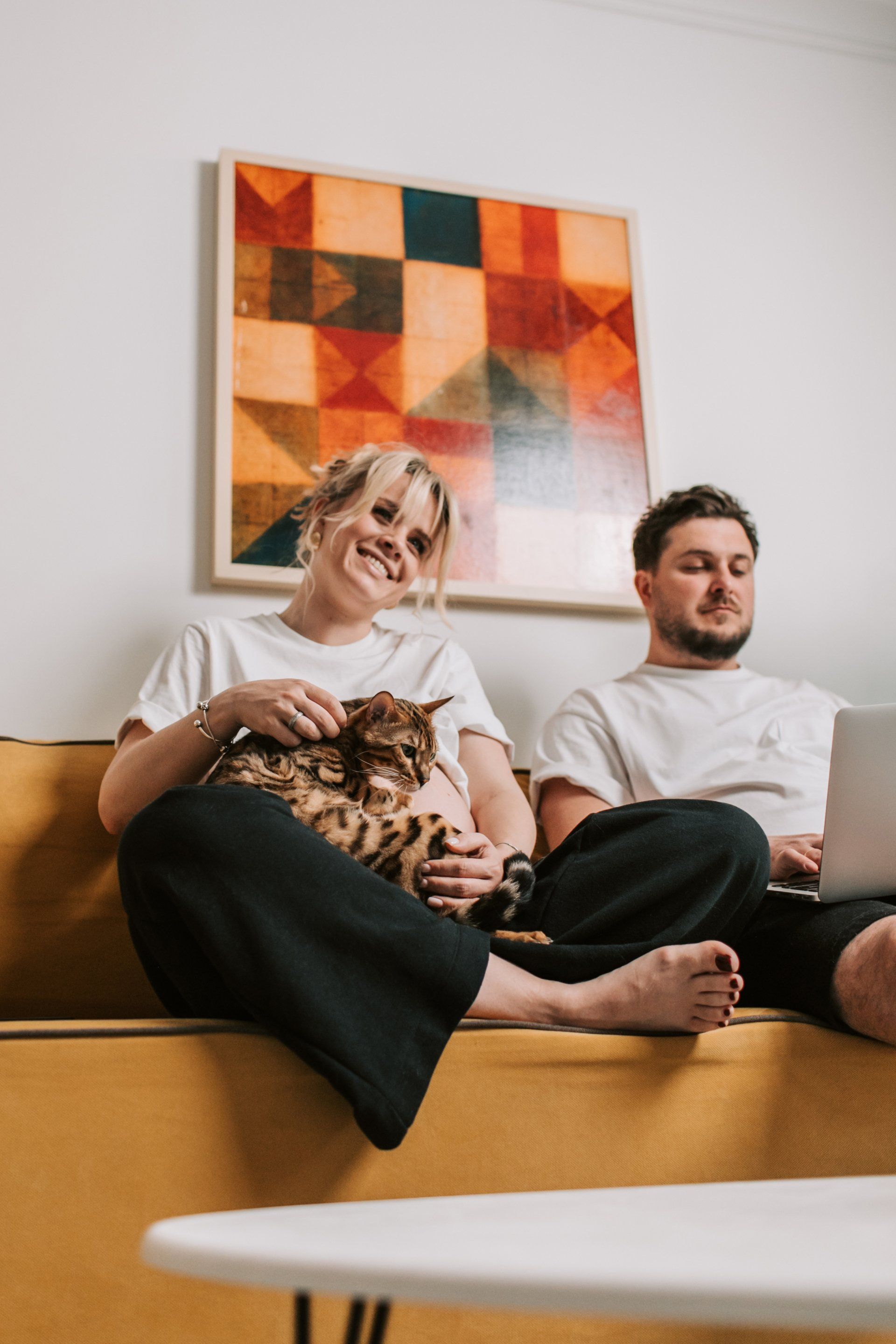 Couple on couch with woman holding a cat and smiling
