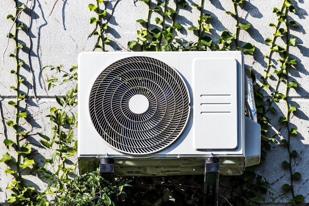 Outdoor air conditioner unit with ivy plants growing beside it | Energy-Efficient HVAC