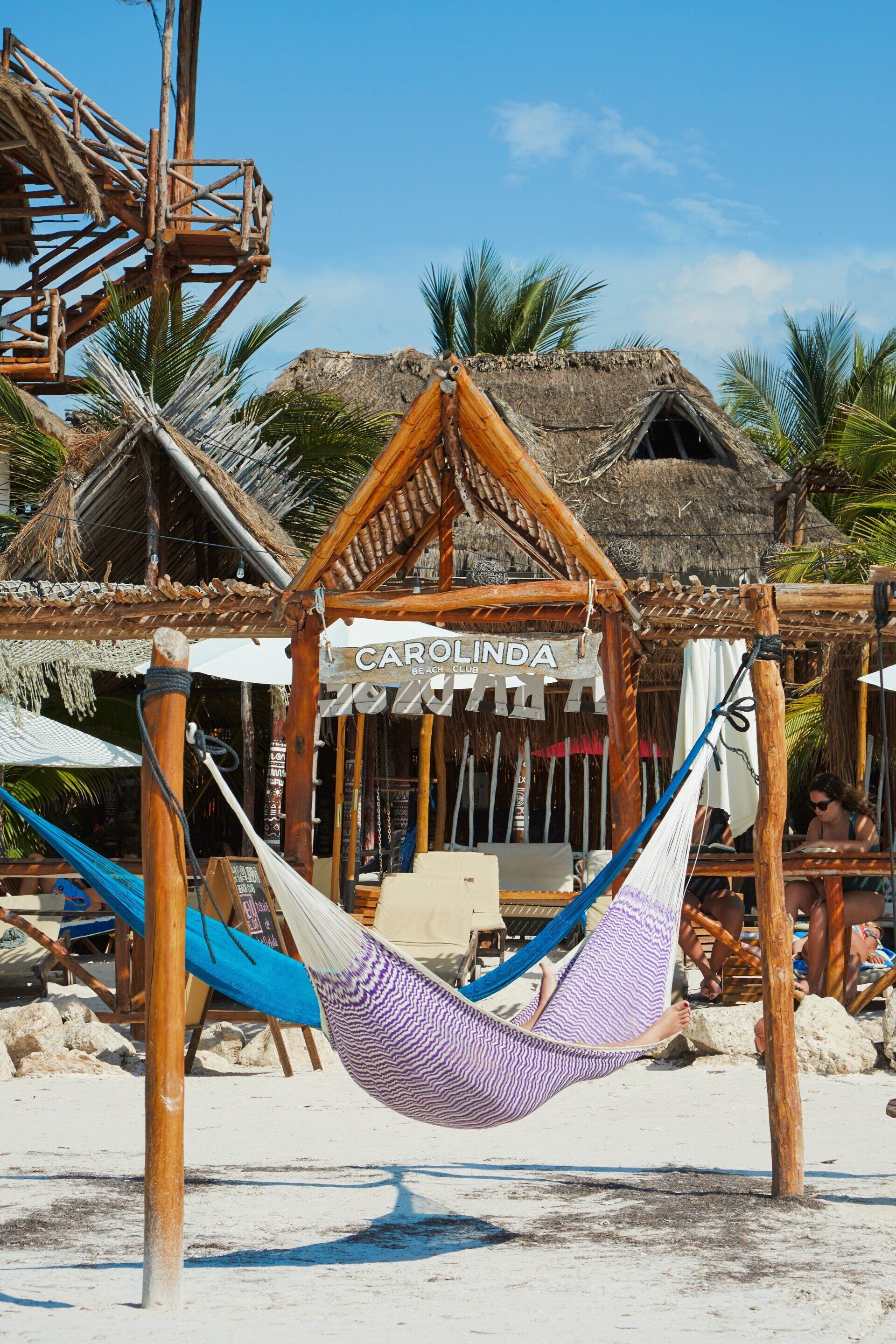 A hammock is hanging from a wooden post on a beach.