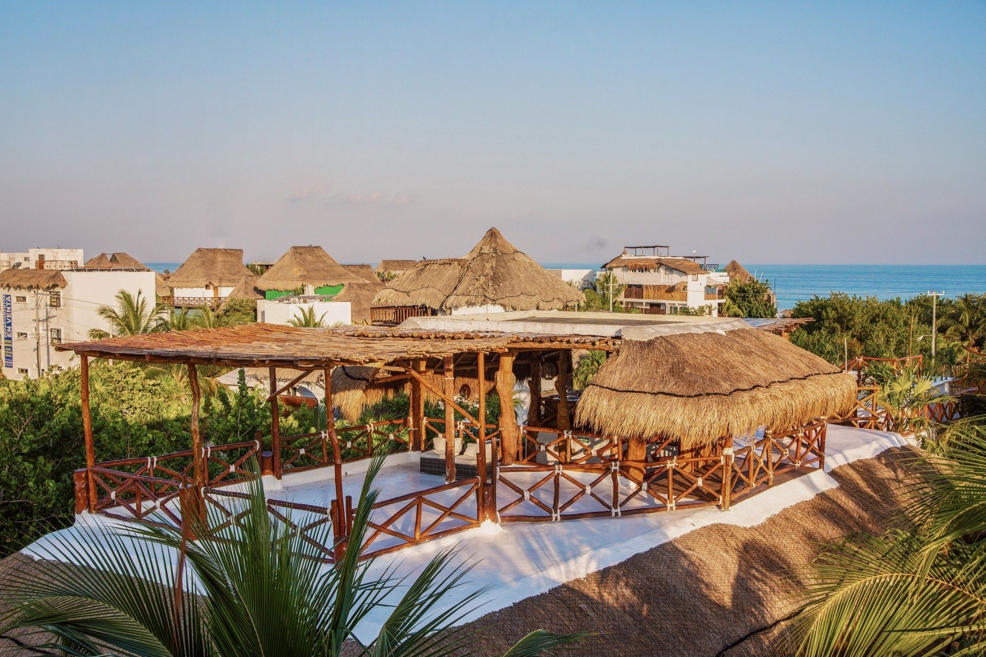 A view of a beach resort with thatched roofs and palm trees.