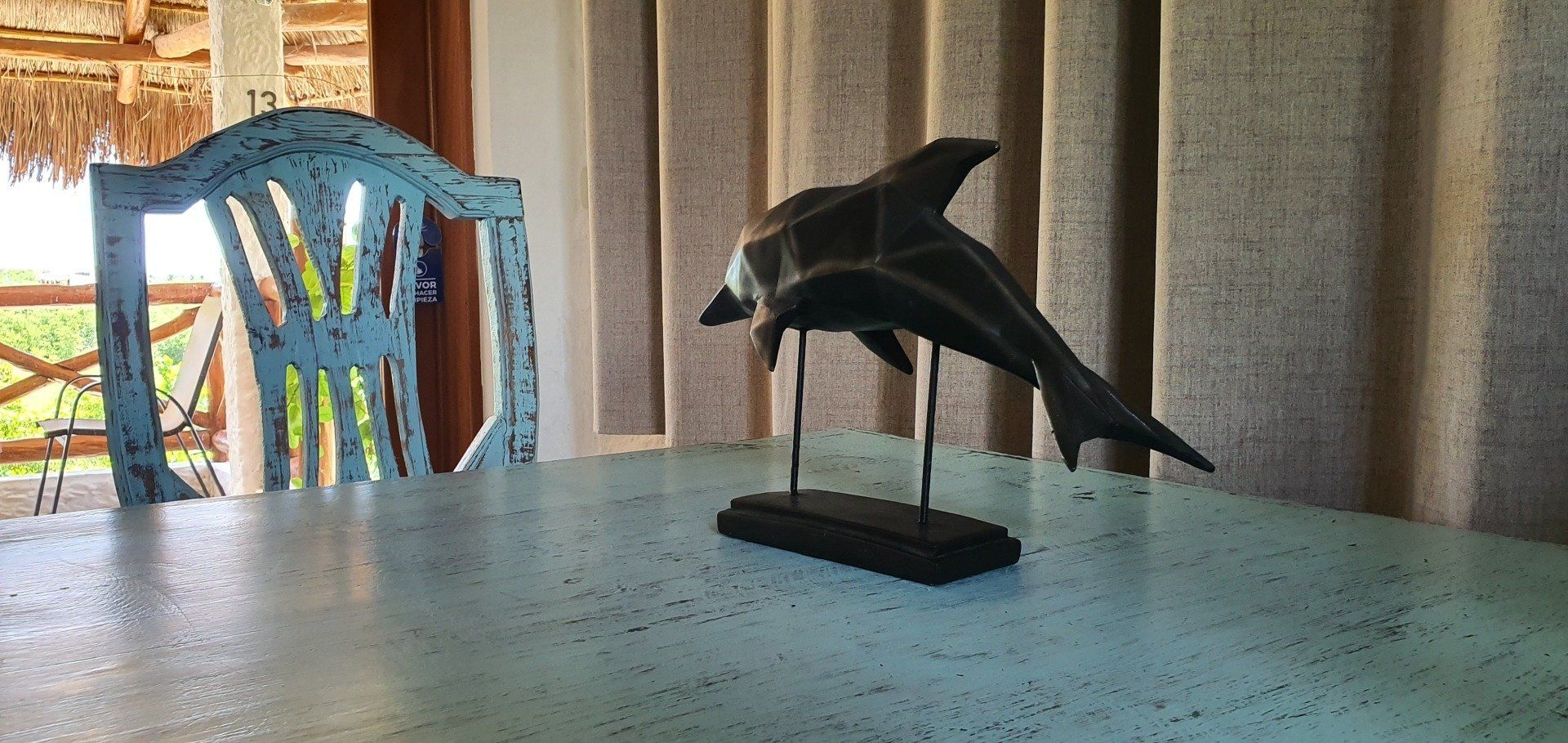 Una estatua de un delfín está sentada en una mesa al lado de una silla.