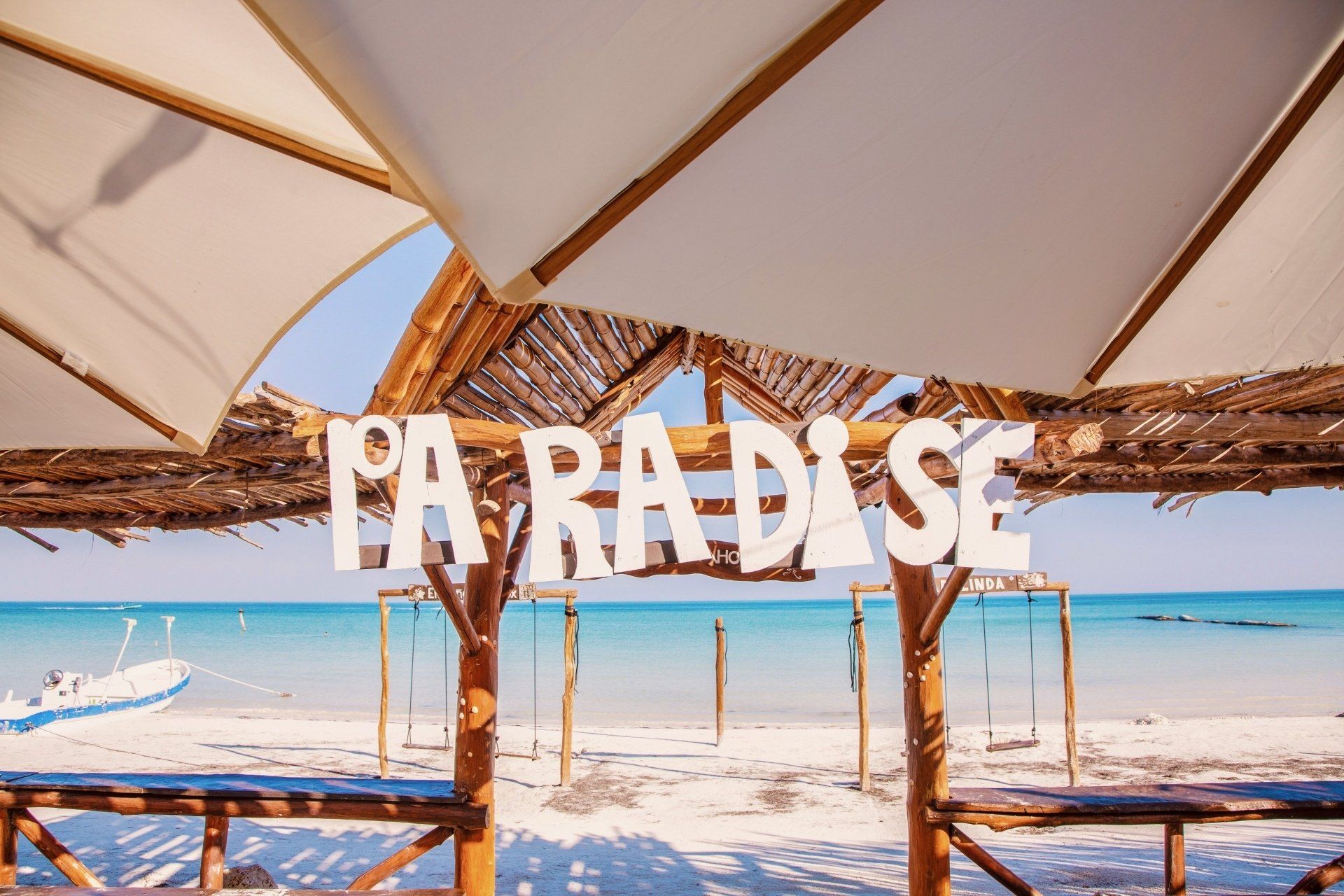 A sign on a beach that says paradise