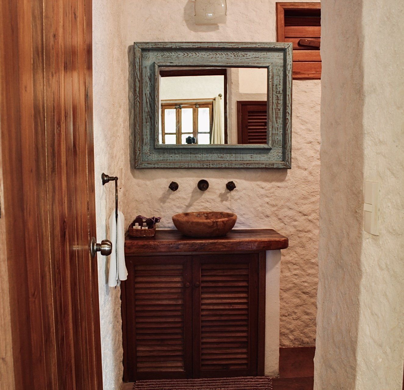 Un baño con lavabo de madera y espejo.