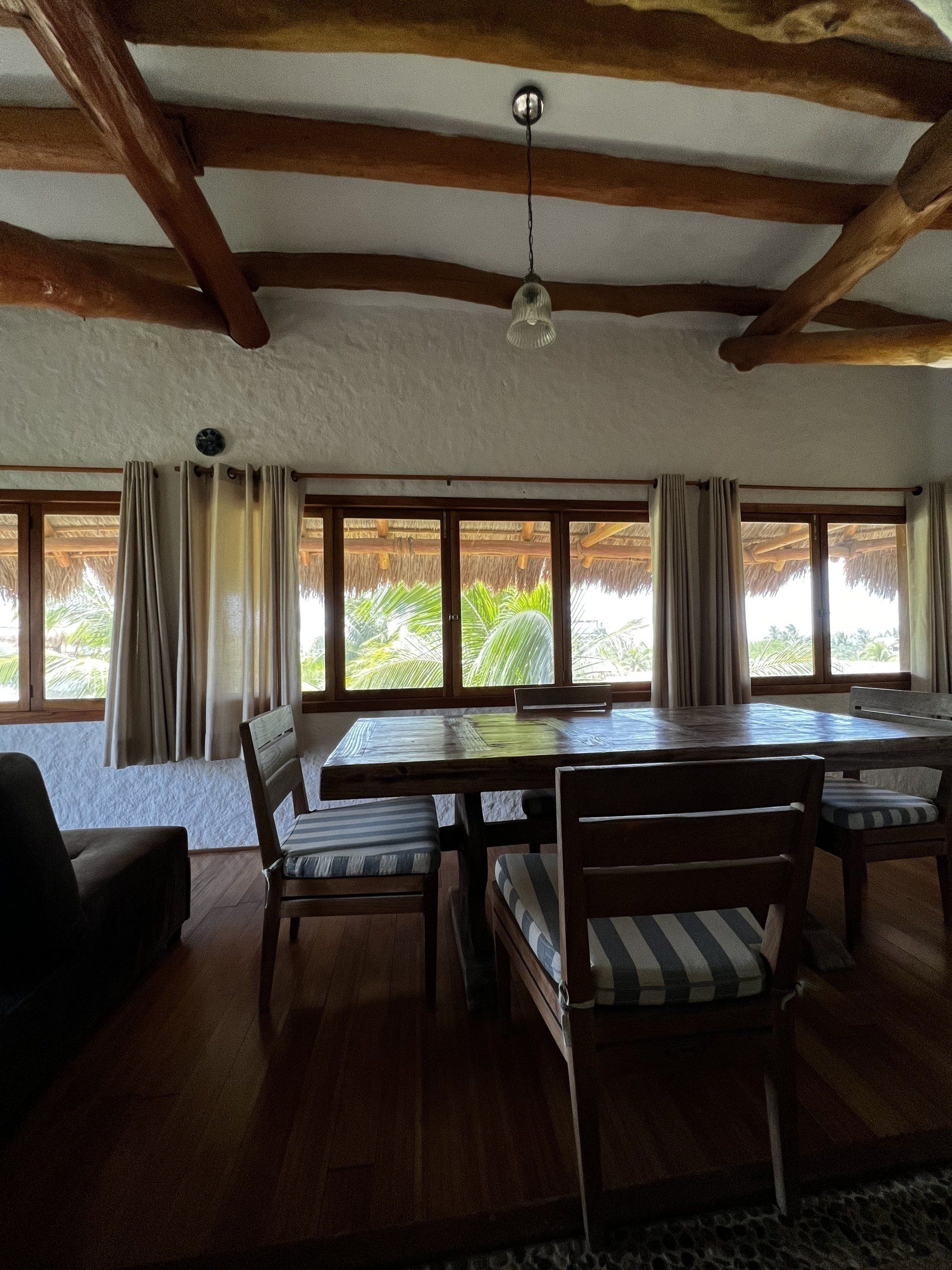 Una sala de estar con mesa y sillas y muchas ventanas.