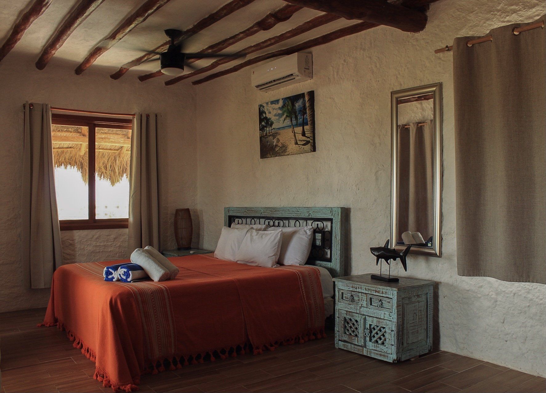 Un dormitorio con cama, mesita de noche, espejo y ventilador de techo.
