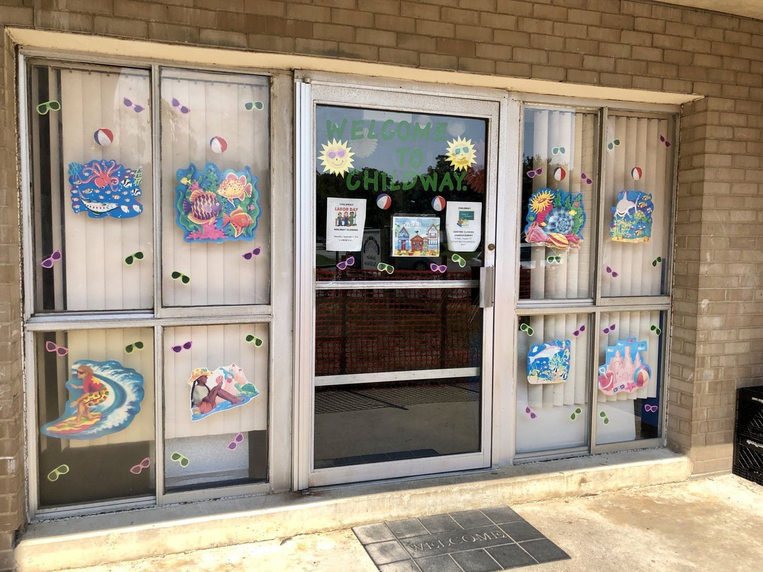 Storefront windows decorated with colorful holiday art and a central glass door labeled “CHM”