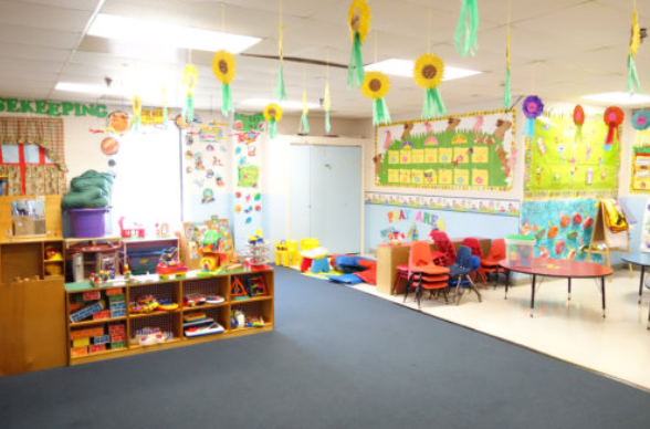 Colorful kindergarten classroom with toys, tables, chairs, and hanging sun decorations