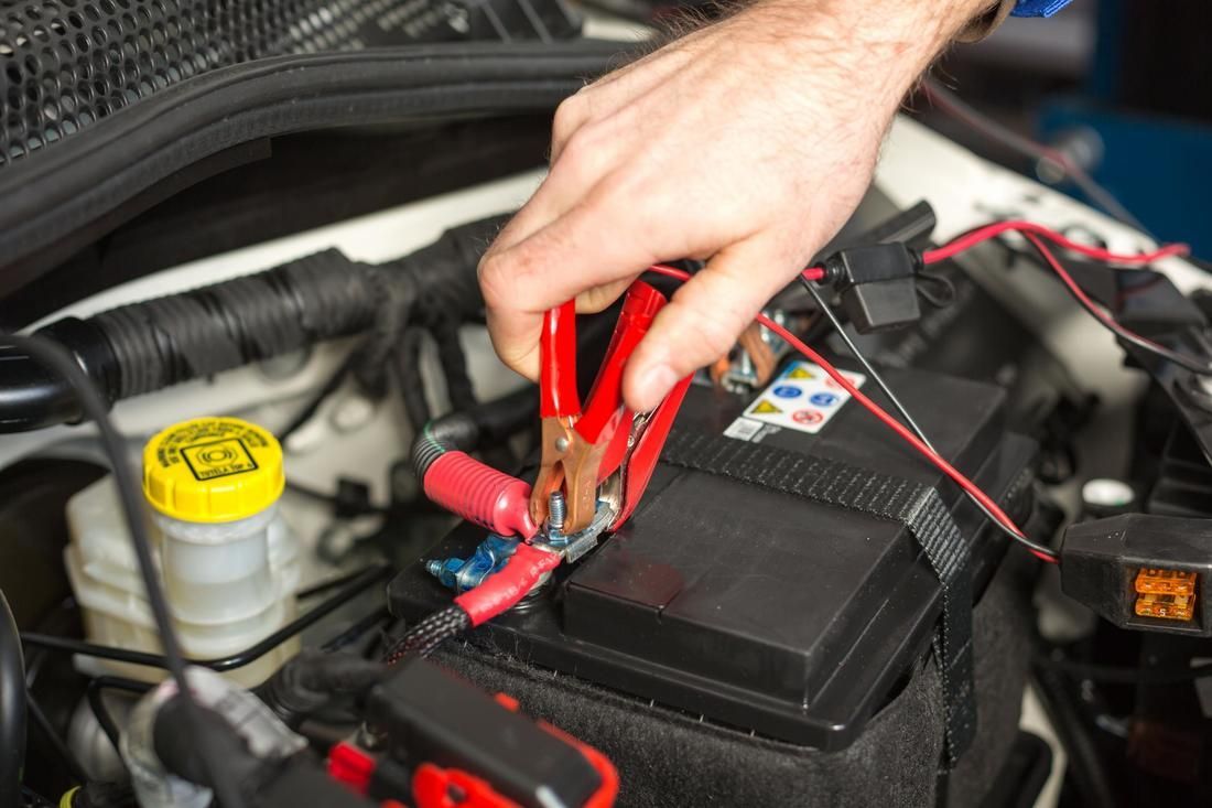 A person is charging a car battery with a jump starter.