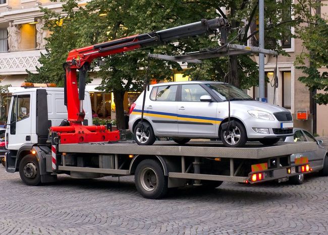 A tow truck with a car on the back of it.