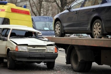 A tow truck is towing a car that has been damaged in a car accident.