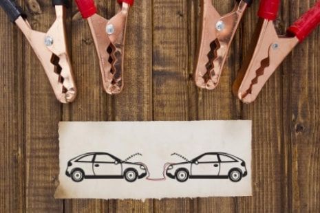 A picture of two cars being charged with copper clamps on a wooden table.
