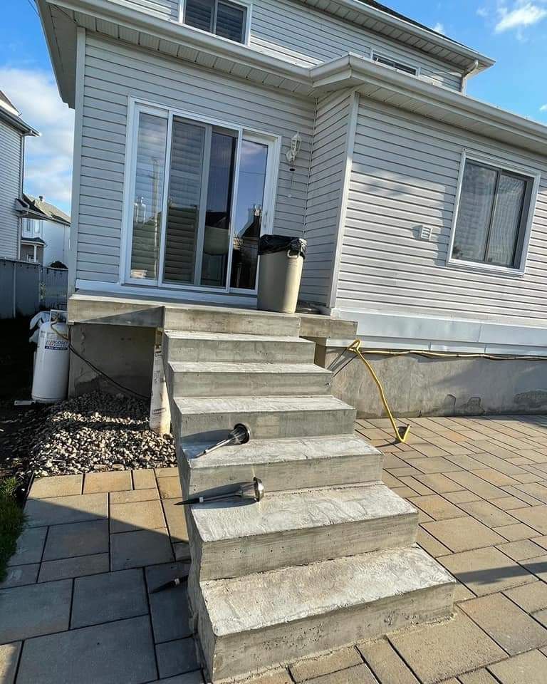 A house with stairs leading up to it and a trash can in front of it.