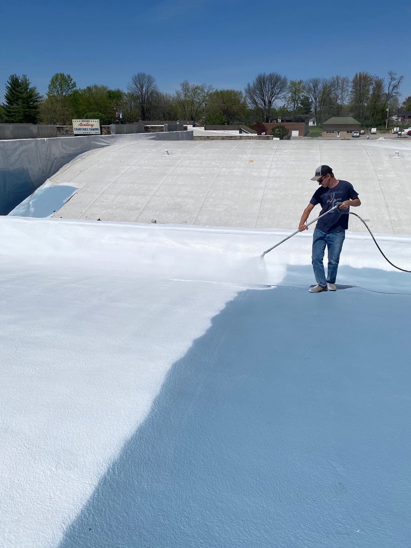 A man is painting a roof with a sprayer