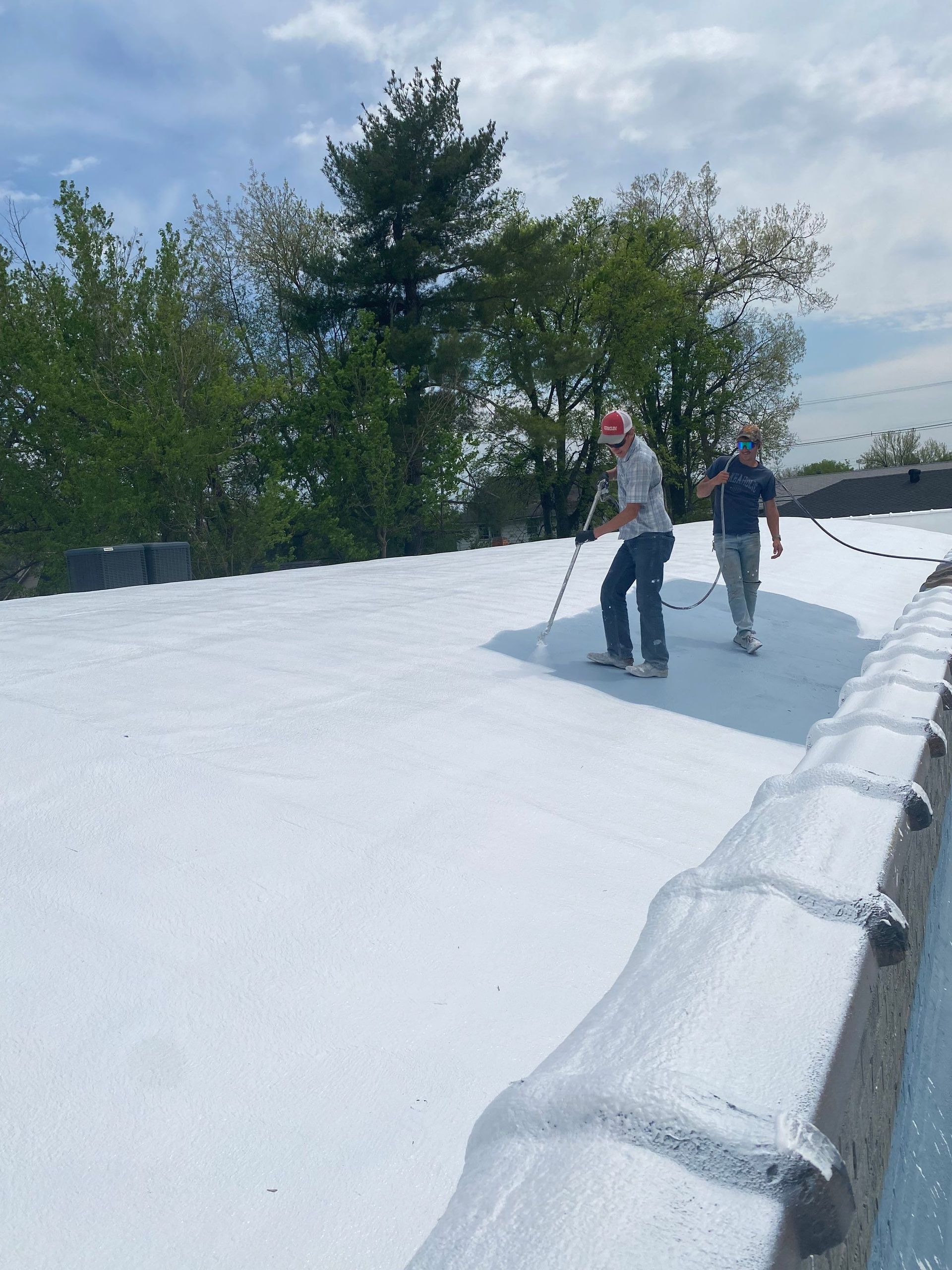 Two men are standing on top of a snow covered roof
