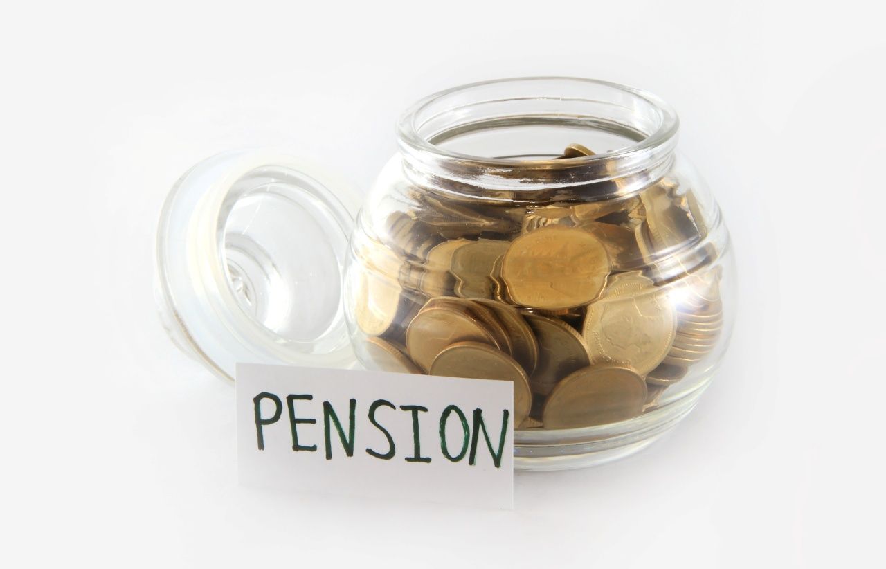 pension written on a piece of paper with a glass jar full of coins