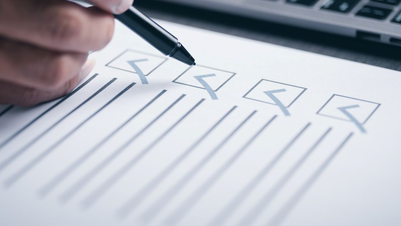 hand holding a pen checking boxes on a paper