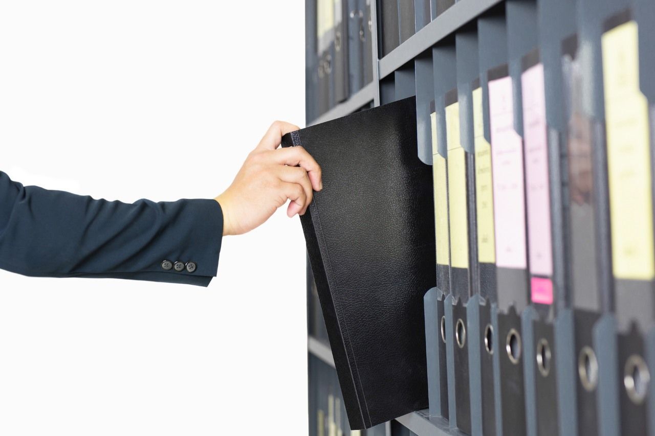 hand pulling out a file from a shelf