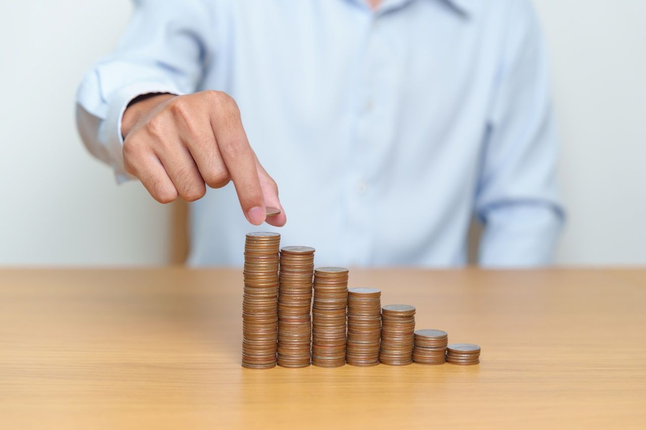 man stacking up coins on a wooden table