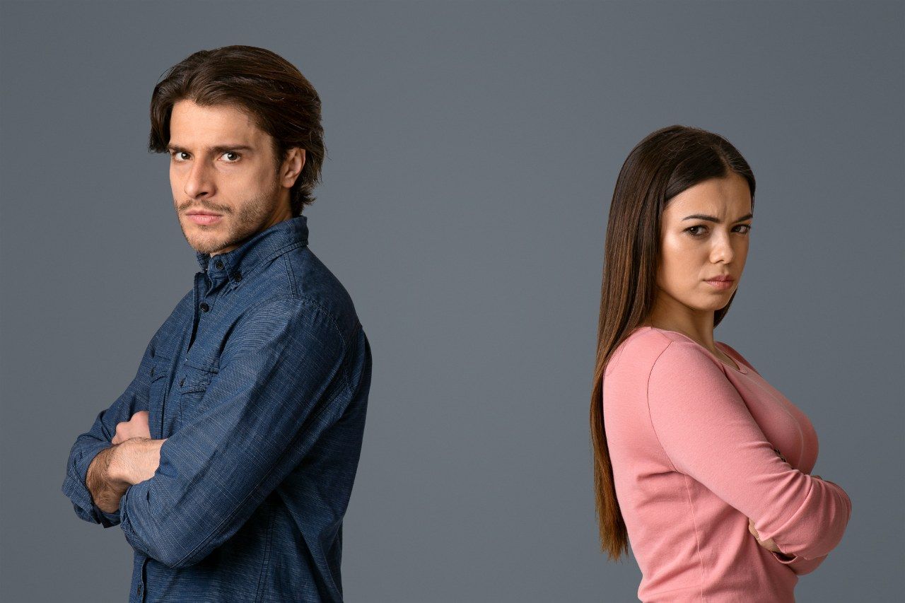 man and woman standing back to back with folded arms