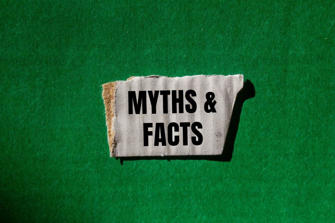 words myths and facts in a torn piece of cardboard on green background