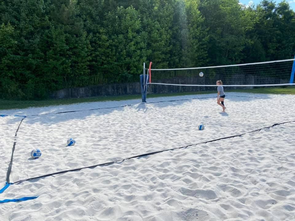 A woman in a red dress is playing volleyball on the beach