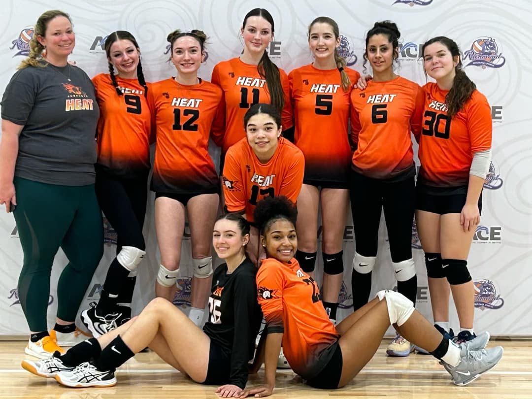 A group of girls are posing for a picture on a volleyball court.