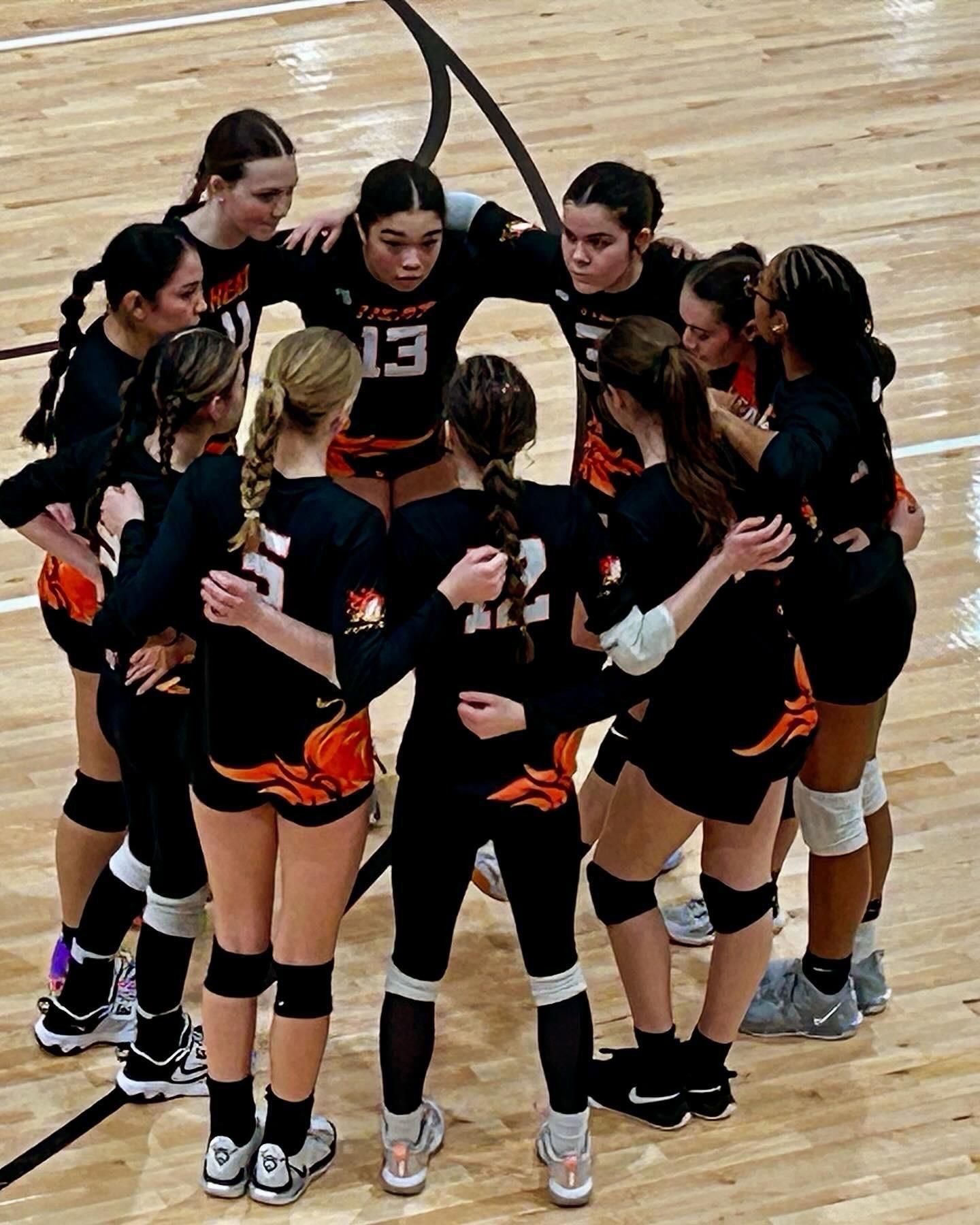 A group of volleyball players are huddled together on the court.