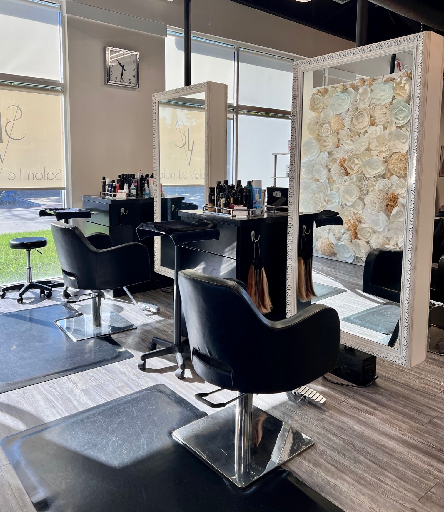 Close-up of two large beautiful mirrors in front of black padded styling chairs.