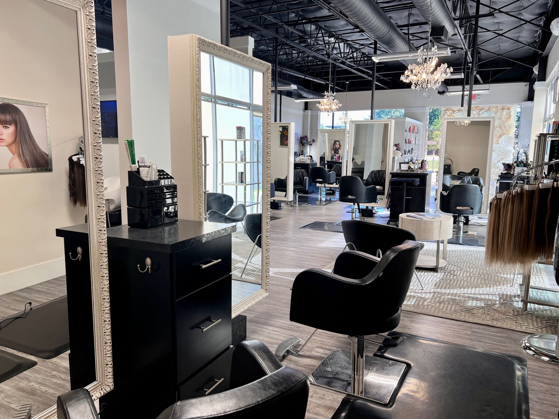 Close-up of one styling station with large framed mirror and black padded styling chair.