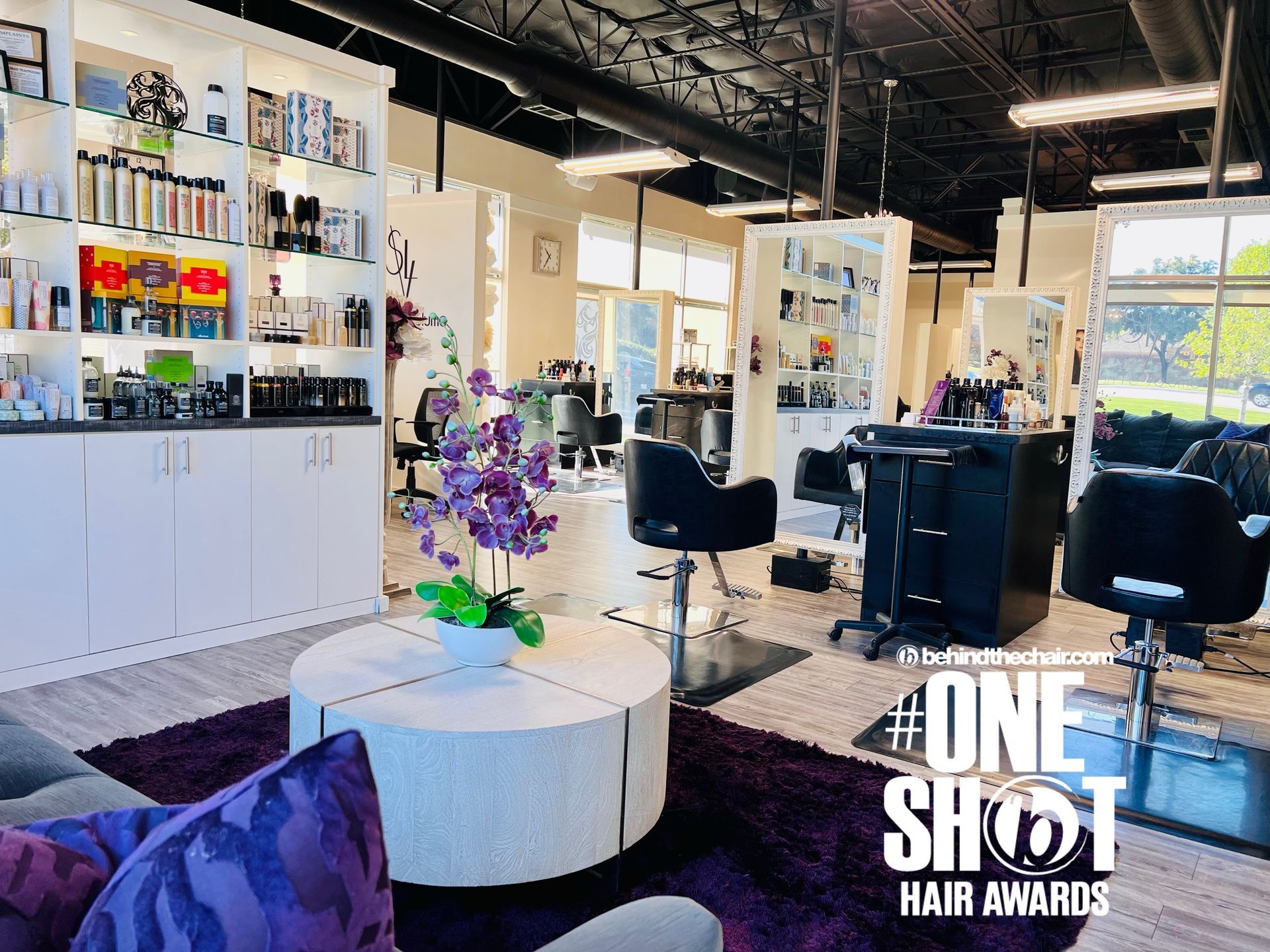 Elegant hair salon with orchids on small round table & large white picture-frame mirrors in front of each styling chair.