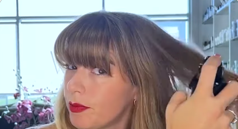 Kristina spraying heat protectant into her hair
