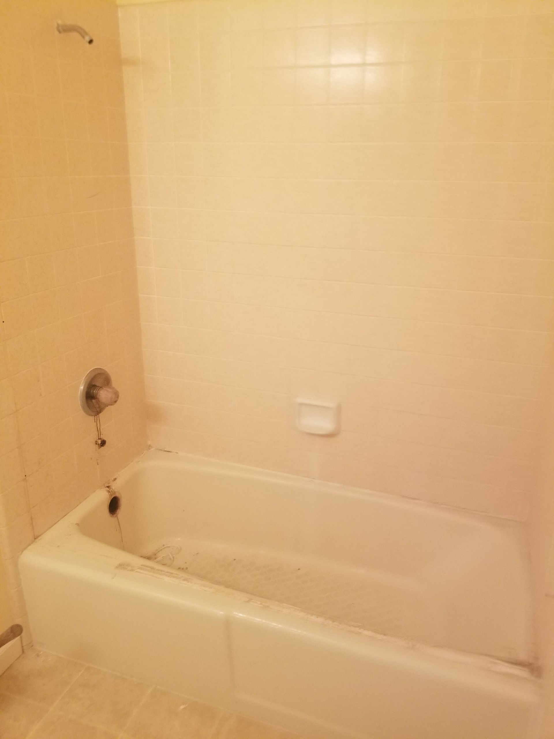 White bathtub with beige tiled walls.