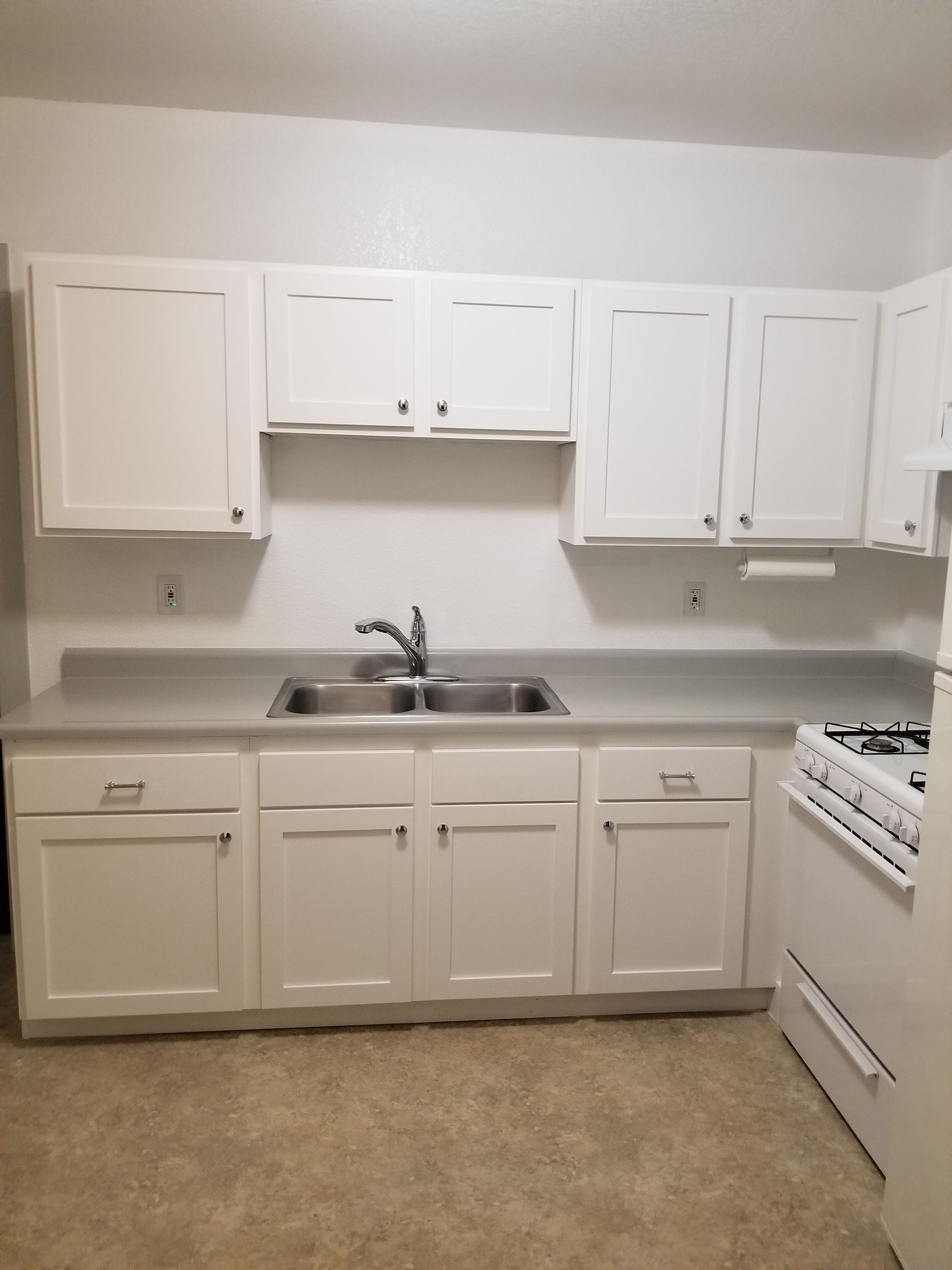 A kitchen with light gray cabinets, a built-in oven, and a skylight. A kitchen with light gray cabinets, a built-in oven, and a skylight.