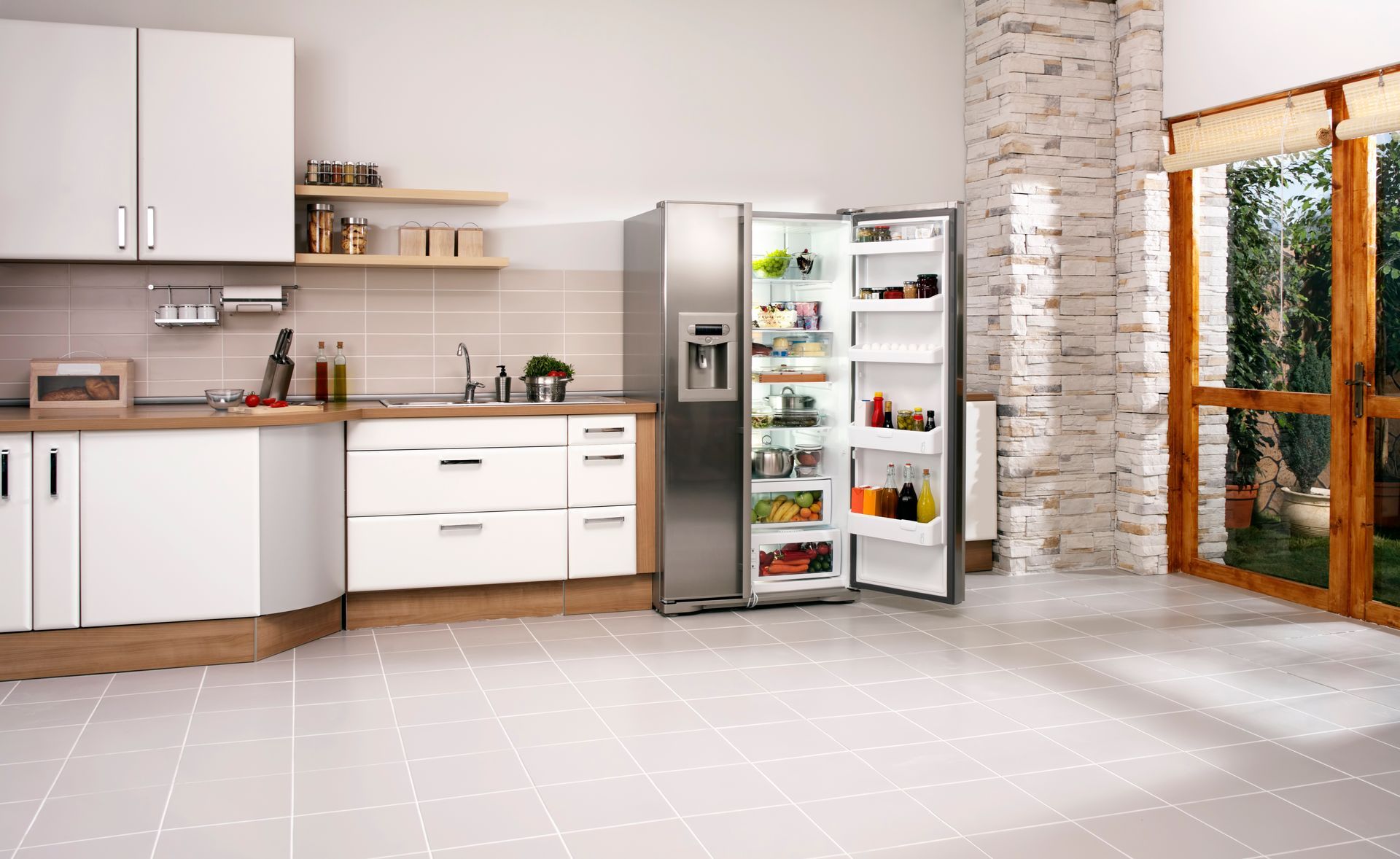 Modern kitchen with open stainless steel refrigerator filled with food, bright white cabinetry.