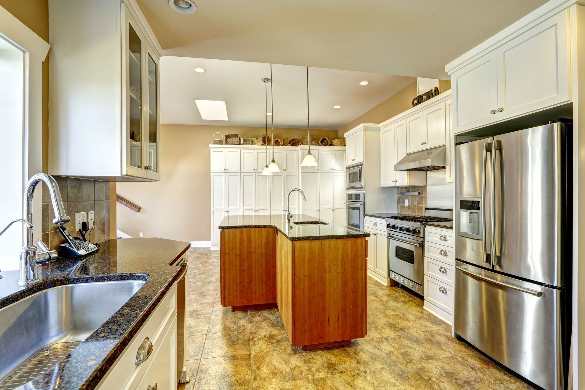 Bright kitchen with white cabinets, stainless steel appliances, and a dark countertop island.