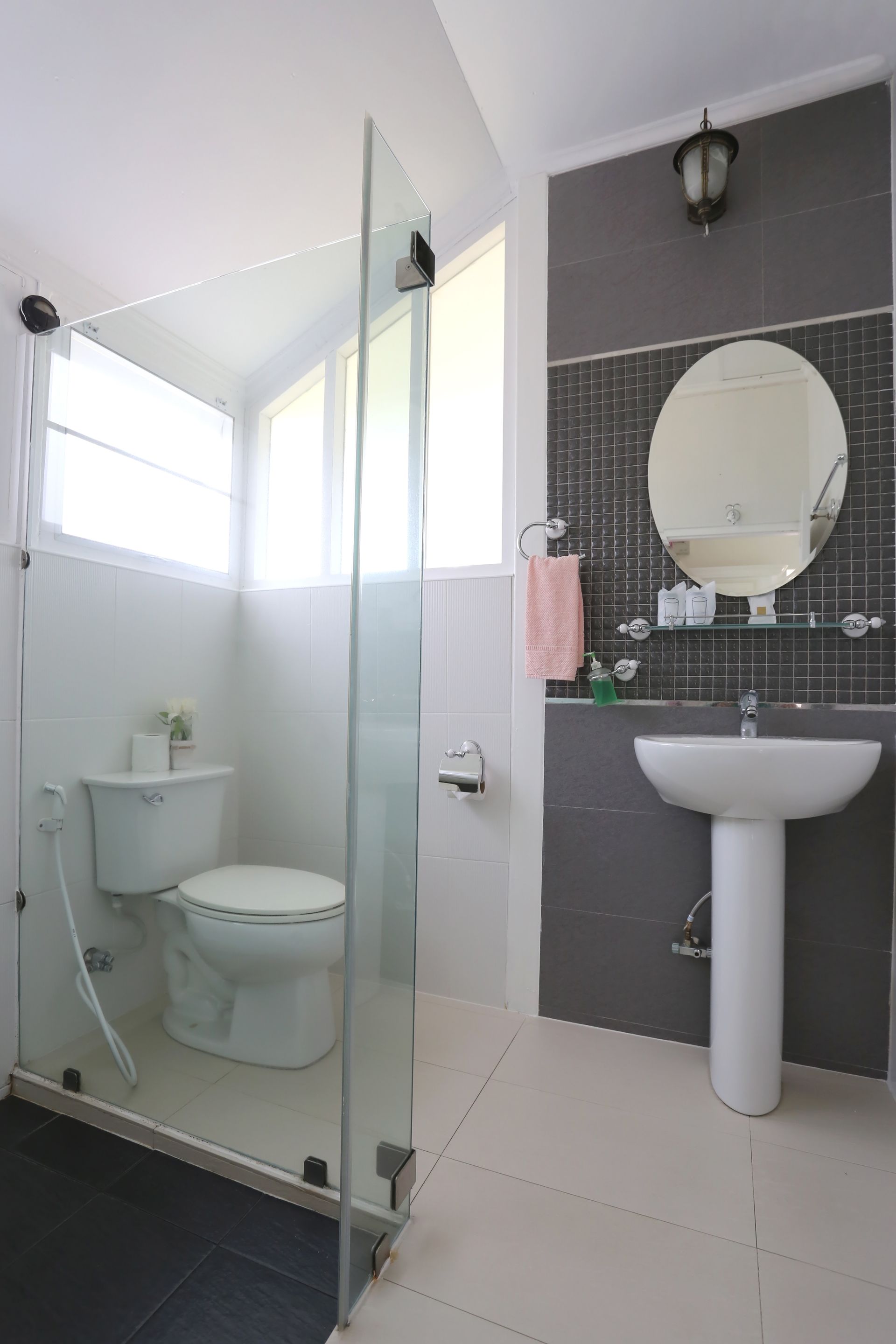 Modern bathroom with toilet, sink, shower screen, and gray accent wall. White, black, and glass elements.