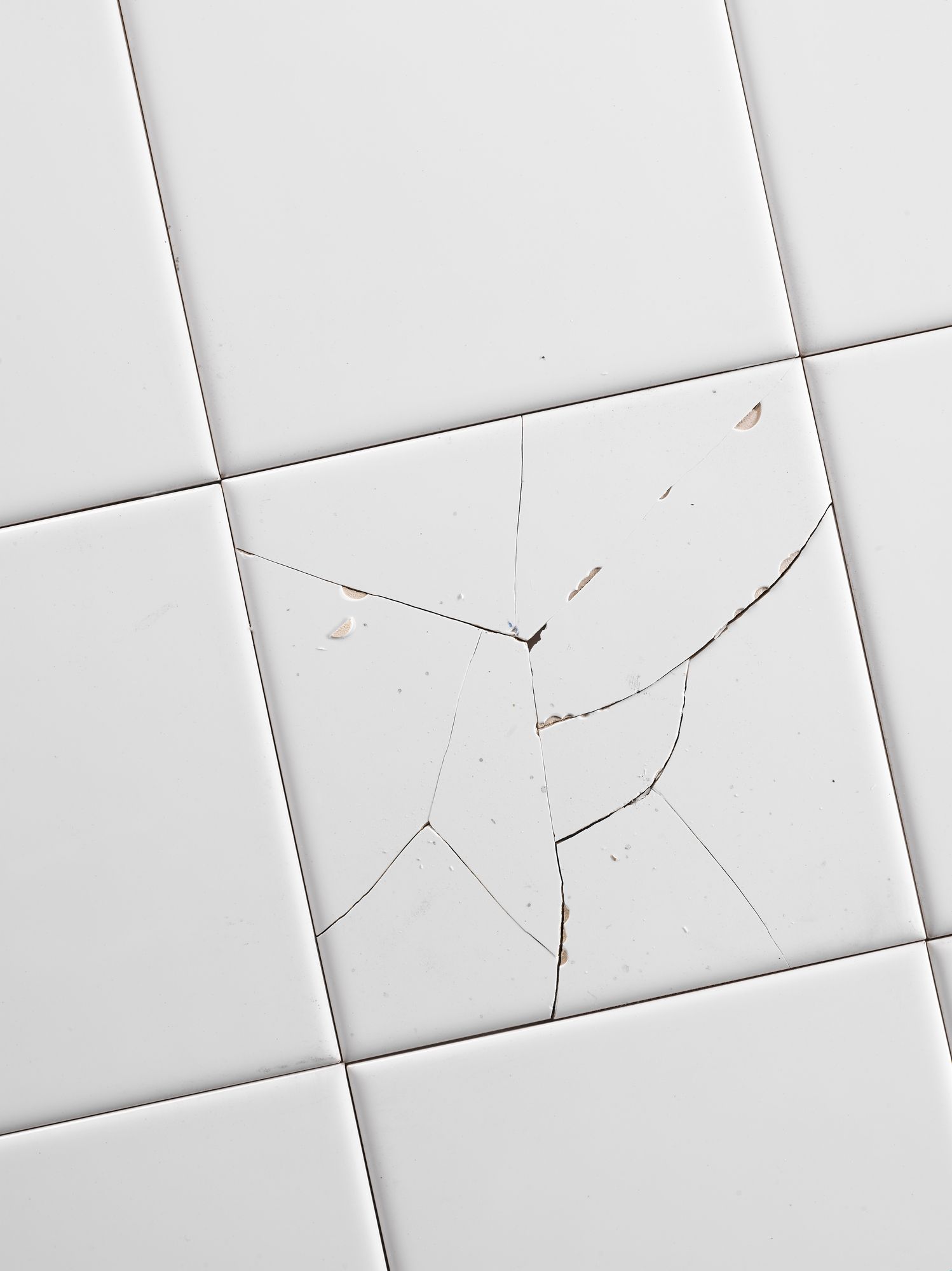 White tile floor with a cracked tile in the center.
